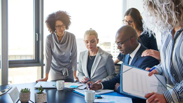 Employees discussing reports and charts around a table