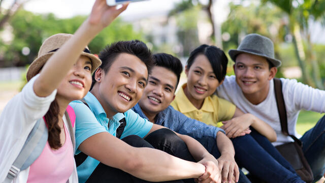 Teens taking a "selfie" picture together outside
